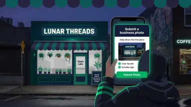 Smartphone pointed at a storefront sign that matches the Google Business Profile name, with the whole facade in one frame